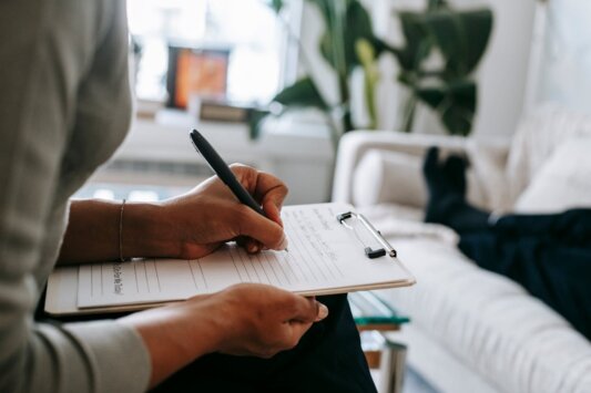 Iperattività https://www.pexels.com/photo/crop-ethnic-psychologist-writing-on-clipboard-during-session-5699456/